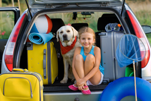 Girl and dog in the boot of a car going on a car journey