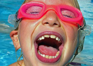 Young kid with goggles smiling in a swimming pool