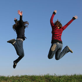 Two travelling teenagers jumping in the air