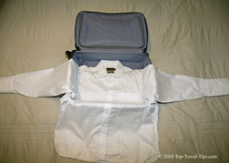 Shirt layed over carryon luggage as first part of bundle wrapping packing