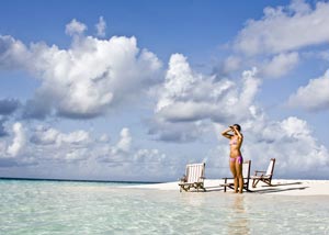 Single woman on a beach watching out on to the sea