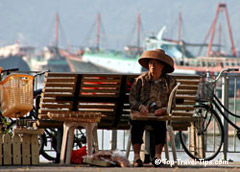 Elderly woman with hat sitting on a bench in Vietnam