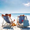 Two people sitting on beach chairs on a beach