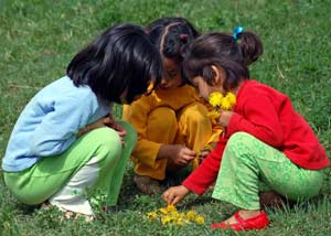 Three young girls playing with flowers