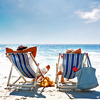 Two people sitting on beach chairs on a beach