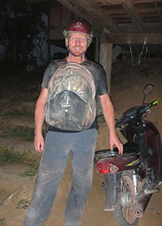Driving the Loop turns you orange Man standing next to motorcycle driving the Laos Loop